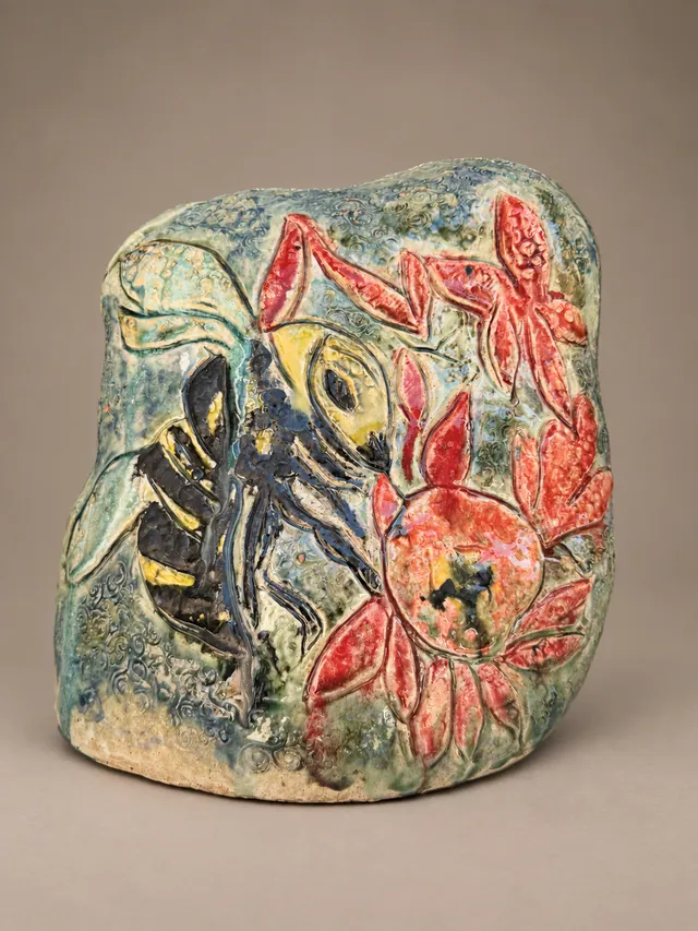 Rounded turquoise slab with a bee and red flowers in relief