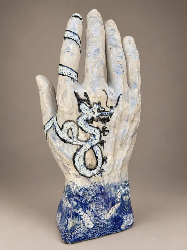 Hand sculpture with a painted dragon and a cobalt cuff