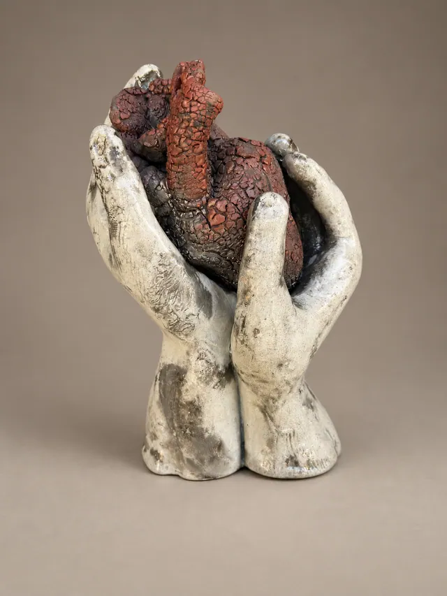 Two hands cradling a red heart