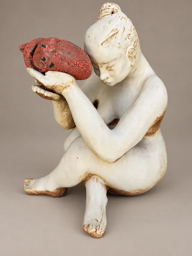 Seated white figure cradling a red heart
