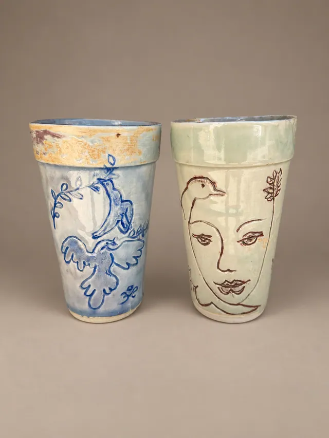 Two tumblers with a bird and a face in blue and brown line